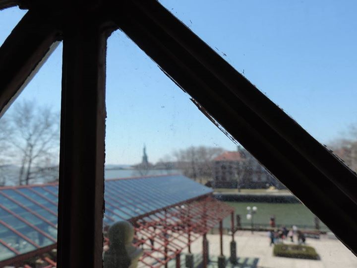 La Statua della Libertà a portata di mano, dietro un vetro di un edificio di Ellis Island